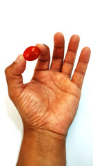 Black male hand holdig a ripe cherry tomatoes with fingers on the white background.
