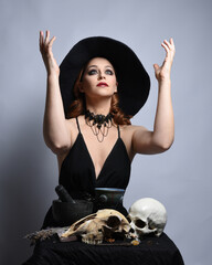 Close up portrait of beautiful  female model wearing black dress, pointy witch hat halloween...