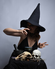 Close up portrait of beautiful  female model wearing black dress, pointy witch hat halloween...