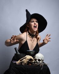 Close up portrait of beautiful  female model wearing black dress, pointy witch hat halloween...