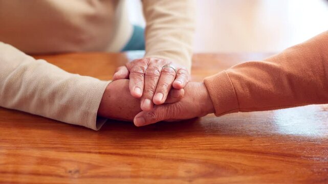 Senior people, grief and compassion with holding hands, support and assistance in nursing home or retirement. Elderly couple, bonding and empathy in living room for love, connection or communication