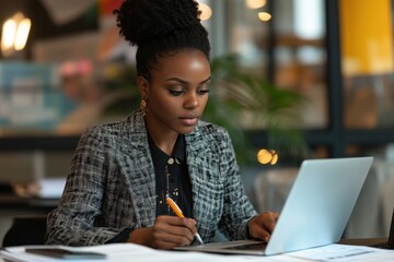 Female leader reviewing financial statements with laptop and smartphone