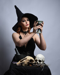 Close up portrait of beautiful  female model wearing black dress, pointy witch hat halloween...