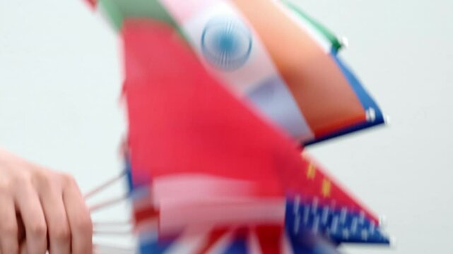 Vertical video. Global unity. International relations. Cultural diplomacy. Peace solidarity. Female hand waving world flags isolated on light.