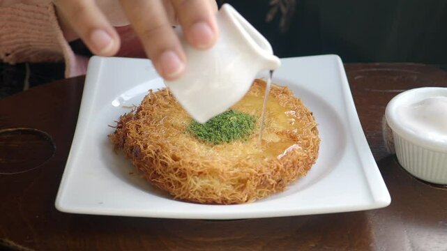 pouring cream ob Turkish dessert kunefe, 