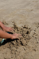 Close up of a child's hand squeezing sand at the beach. Concept for kids outdoors activity