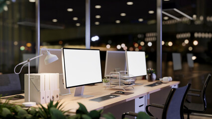 A close-up of computer desks in a modern office on a skyscraper at night.
