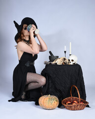  portrait of beautiful female model wearing glamorous black witch dress, pointy hat halloween...
