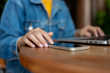 A close-up of a woman's finger tapping on a smartphone screen placed on a table.