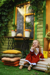 little girl sitting on a chair and looking at the camera. Little girl of two years old in a hat and a beautiful vintage dress. Beautiful little child walking in the garden