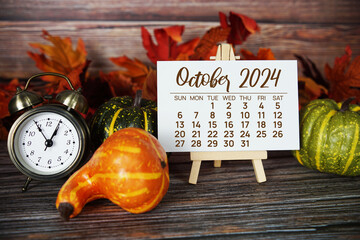 October 2024 monthly calendar with maple leaf on wooden background