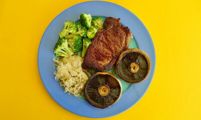 A porterhouse steak with mushrooms broccoli and sauerkraut.