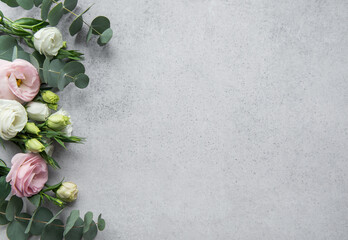 Delicate arrangement of mixed  flowers and eucalyptus leaves on a light grey surface