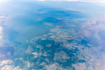 Fototapeta premium View from the airplane window at a beautiful blue clear sky, earth, sea and the airplane wing