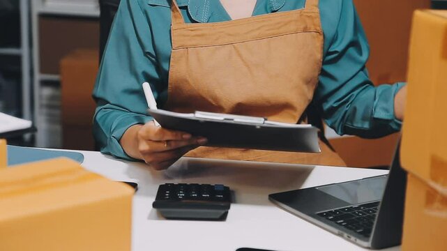 Startup SME small business entrepreneur of freelance Asian woman using a laptop with box Cheerful success Asian woman her hand lifts up online marketing packaging box and delivery SME idea concept