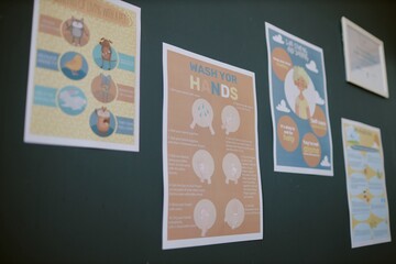 Various educational posters are displayed on the wall, featuring detailed instructions and graphics for proper hand-washing procedures and hygiene tips