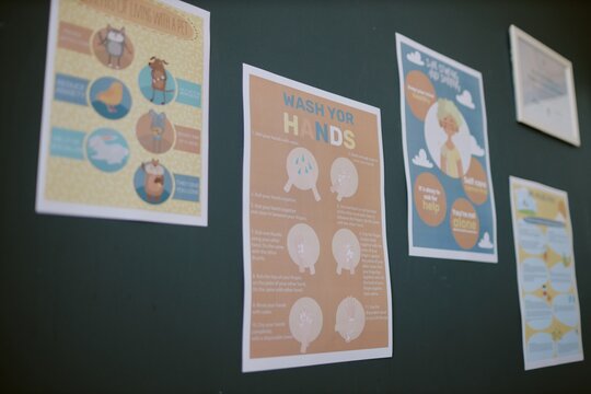 Various educational posters are displayed on the wall, featuring detailed instructions and graphics for proper hand-washing procedures and hygiene tips