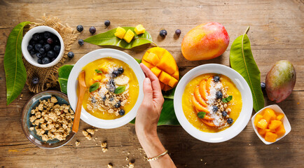 Top View of Smoothie Bowl with Mango, Blueberry, and Coconut Held by Female Hand – Healthy Breakfast