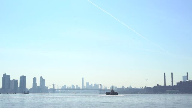 Williamsburg Bridge in the distance with a helicopter and boat in view