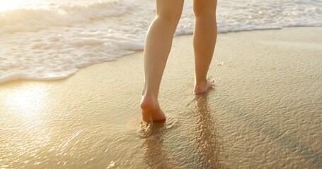 Person, legs or feet with water on beach, waves or shore for sunny vacation, holiday or weekend getaway in nature. Closeup, walking and foot with sunlight on ocean coast for outdoor stroll by seaside