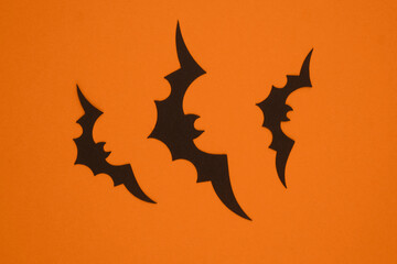 Black bats flying against an orange background during Halloween celebrations in autumn
