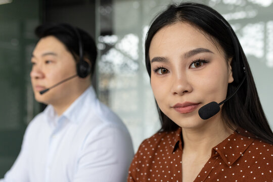 Focused asian business professionals wearing headsets working in customer service setting. Engaged in communication, demonstrating attentive interaction with clients.