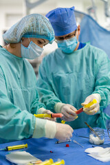 Staff readying tools for surgery. Two healthcare workers in scrubs meticulously prepare surgical...