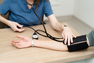 Nurse checks blood pressure in exam. A healthcare professional measures a patient's blood pressure...