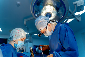 Surgeons in a high-tech hospital. Two surgeons in surgical attire work intently during a surgical...