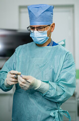 Surgeon readying tools in sterile OR. A surgeon dons surgical attire, meticulously preparing...
