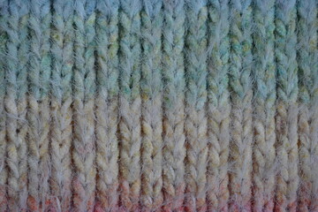 Macro texture of acrylic multicolored rainbow pastel crocheted winter clothing sweater as background, close-up of rainbow front surface, multicolored wool texture, crocheted front surface, part of sca