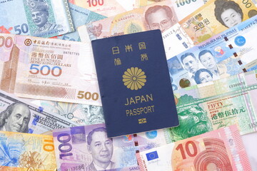 日本のパスポート（一般旅券5年用紺色）と、さまざまな国の通貨の紙幣で、海外旅行のイメージ
