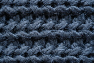 macro texture of woolen dark gray crocheted sweater as background, close-up of gray crocheted front surface, woolen texture of woolen wool, knitted front surface