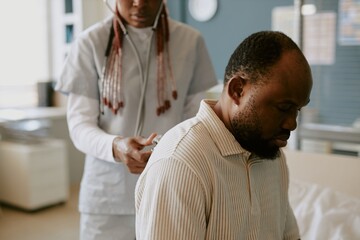 Doctor using stethoscope for diagnosing African American man in medical examination room creating attentive and professional healthcare environment