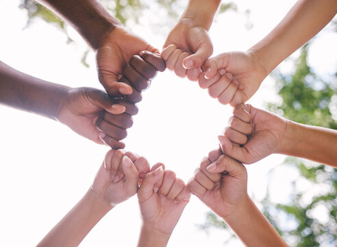 Fist bump, circle and hands of people in park for support, agreement and collaboration in nature. Diversity, volunteer group and below of friends for teamwork, community and solidarity outdoors
