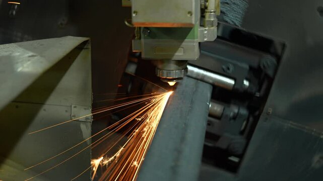 Laser cutting machine for metal pipes. Modern CNC laser machine cutting rectangular metal pipe. Close-up. Bright burning sparks flying during cutting process