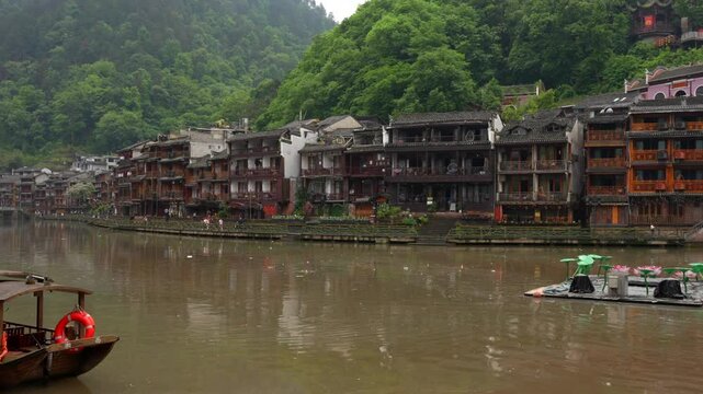 Morning view of Tuojiang River with boats and traditional houses in Fenghuang, China. Panning right shot