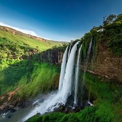 Waterfall cascading from a flat mountain top, lush greenery, dramatic drop, with a clear, tranquil sky backdrop.