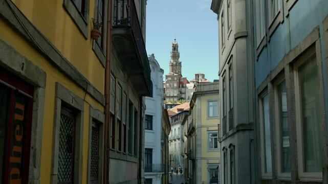 A church tower up on a hill from a street view in Porto, Portugal.