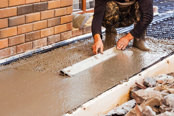Builder pour and level wet ready-mix concrete into formwork during construction of a new blind area