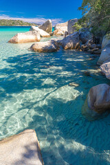 Crystal-clear turquoise water and large, smooth rocks on a peaceful beach surrounded by nature. A perfect spot for relaxation and connecting with nature. A landscape reminiscent of exotic islands. © guteksk7