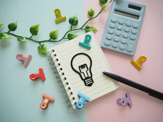 ノートに電球とペン、アイデア出し