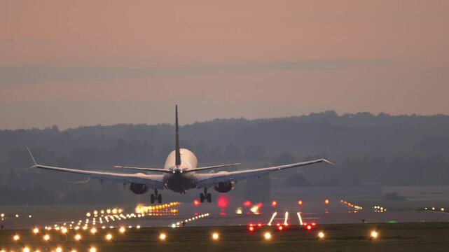 The plane lands at the airport. Commercial Jet Airplane Landing in airport runway at sunset. 