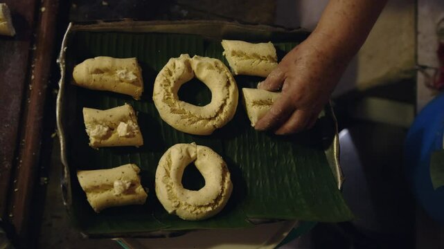 Woman placing Paraguayan chipa on a baking tray with banana leaves to prevent sticking while cooking in the tatakua, a traditional Paraguayan clay oven