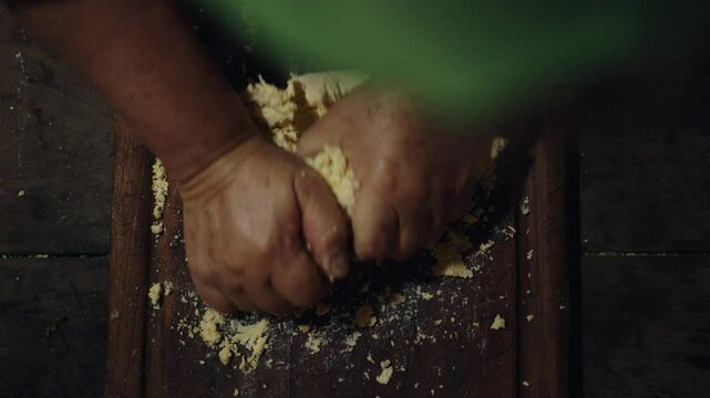 A overhead shot of a woman kneading Paraguayan chipa dough on a wooden table