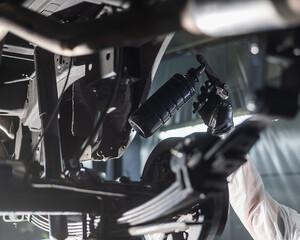 The master sprays an anti-corrosion compound on the bottom of the car. 