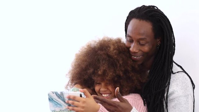 Happy african black family caring young father and smiling teeneger daughter relaxing on couch hugging looking on phone screen watching funny video online