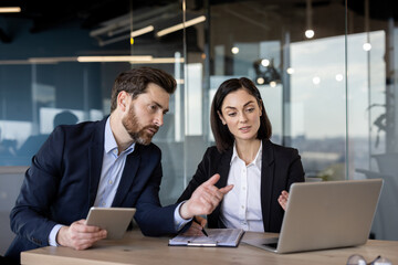 Business colleagues engaged in discussion over project ideas. Man holding tablet , woman pointing...