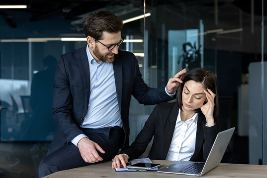 A male boss sexually harasses a female employee of a colleague, two company employees at the workplace inside the office.