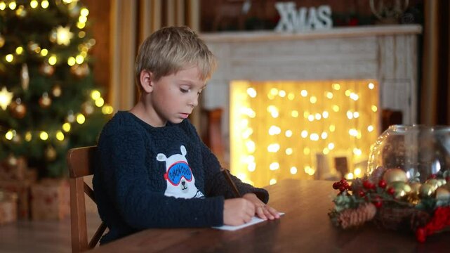 Cute blond child, boy, celebrating Christmas at home, decorated room for the holidays, child reading book and playing